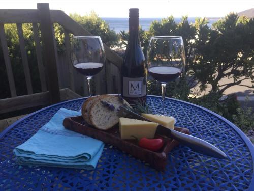 a table with a bottle of wine and cheese and wine glasses at Bicheno Bell in Bicheno