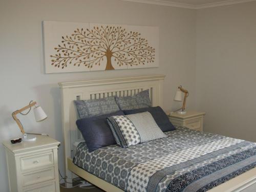 - une chambre avec un lit et un arbre sur le mur dans l'établissement The Clippers 1 fabulous waterfront unit, à Salamander Bay