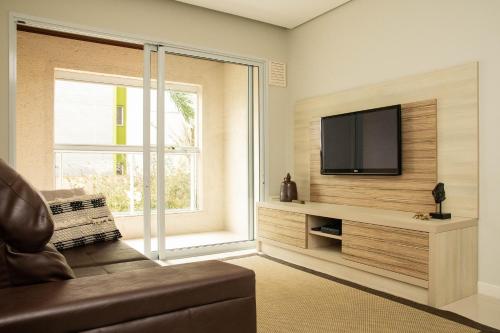 a living room with a flat screen tv on a wall at Apto Costão das Gaivotas, Verde e Mar para Casais in Florianópolis