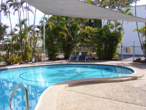 a swimming pool with two chairs and an umbrella at Motel Lodge in Rockhampton