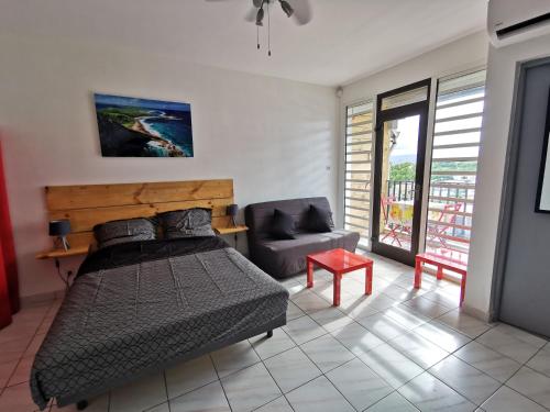 a bedroom with a bed and a couch at Appartement vue mer et montagne à 100m de la plage in Le Gosier