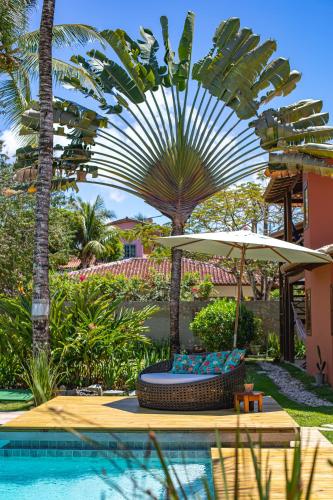 a pool with a chair and an umbrella and palm trees at Pousada Recanto do Arraial in Arraial d'Ajuda