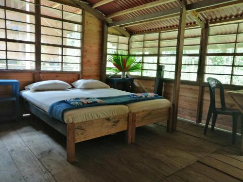 um quarto com uma cama num quarto com janelas em Safio. Una casa en el paraiso. em Nuquí