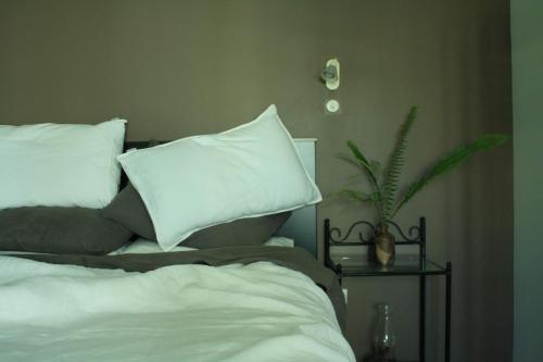 Una cama con almohadas blancas y una planta sobre una mesa en Aquavilla Studio, en Plimmerton