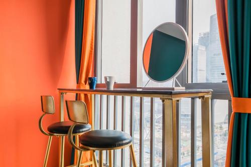 a mirror and two stools in a room with a window at Lavender Apartment in Guangzhou