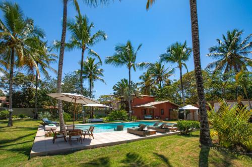 a villa with a swimming pool and palm trees at Pousada Recanto do Arraial in Arraial d'Ajuda