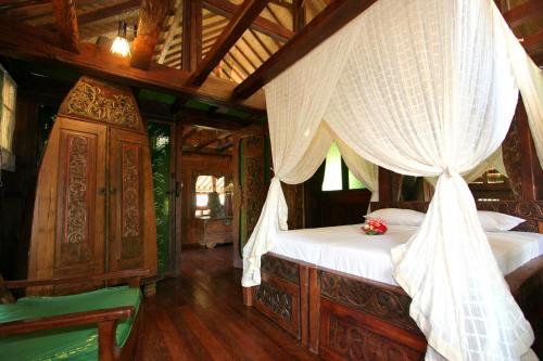 a bedroom with a bed with a canopy at Hotel Pondok Sari Beach & SPA Resort in Pemuteran