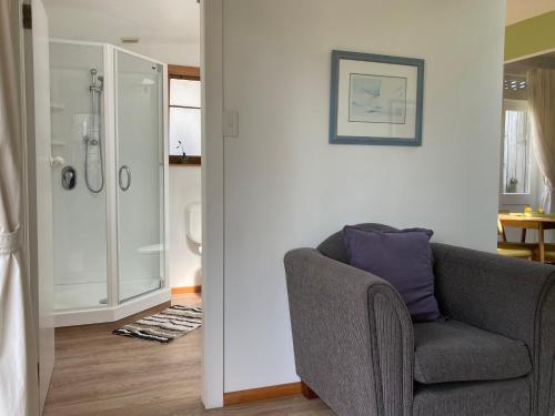 een woonkamer met een stoel en een douche bij Aquavilla Studio in Plimmerton