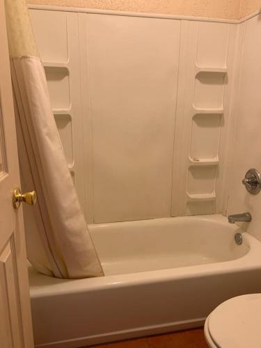 a bathroom with a white tub and a toilet at Western Motel in Deming
