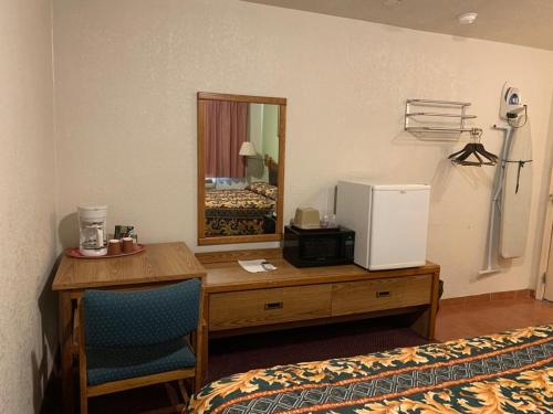 Una habitación con un escritorio, un espejo y una cama. en Western Motel, en Deming