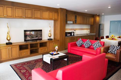 a living room with red furniture and a kitchen at Mosaik Apartment in Pattaya South