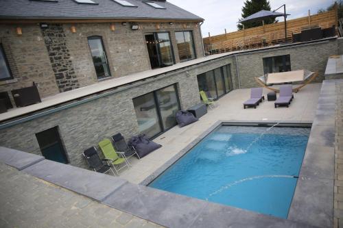 a swimming pool with chairs and a building at Durbuy House in Durbuy