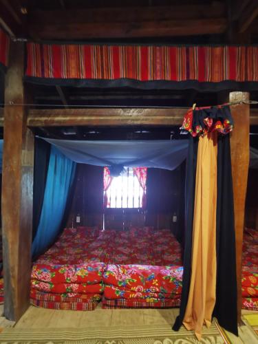 a bedroom with a bed with blue curtains and a window at Lo Lo Homestay & Cafe Meo Vac in Mèo Vạc