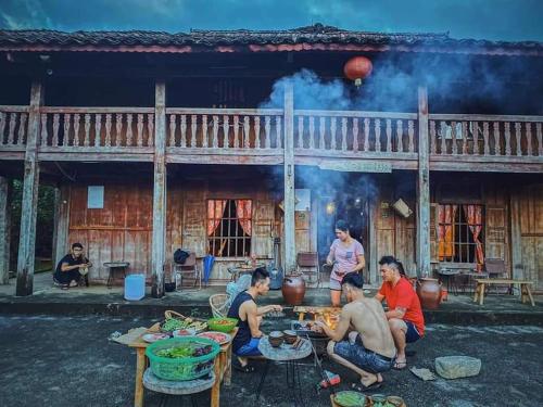 a group of people sitting around a table in front of a building at Lo Lo Homestay & Cafe Meo Vac in Mèo Vạc