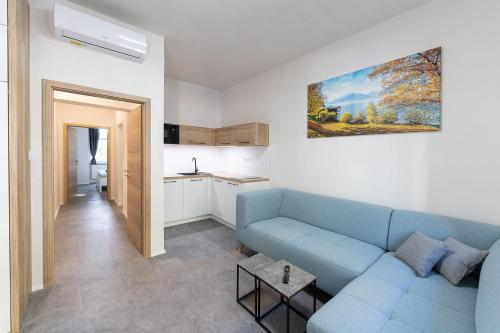 a living room with a blue couch and a kitchen at Apartsee Wellness Plzeň in Pilsen