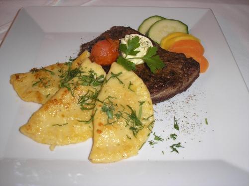 a plate of food with meat and potatoes and vegetables at Gasthof Unterberger in Sankt Kathrein am Offenegg