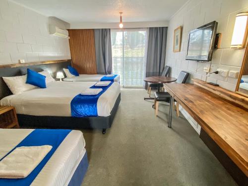 a hotel room with two beds and a desk at Snow Season Motor Inn in Cooma