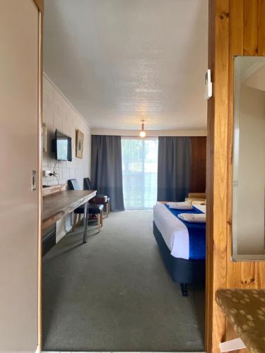 a hotel room with a bed and a desk at Snow Season Motor Inn in Cooma