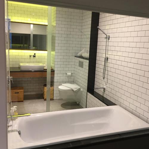 a bathroom with a tub and a toilet and a mirror at Nagomi Suites & Hotel in Jakarta