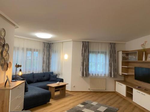 a living room with a blue couch and a television at Almtalhotel Appartements in Pettenbach in Pettenbach