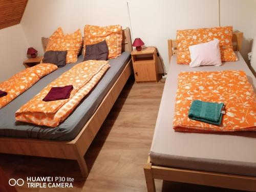two beds in a room with orange comforter at Barackos Vendégház Bár in Bár