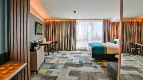 フィリンゲン・シュヴェニンゲンにあるHoliday Inn - Villingen - Schwenningen, an IHG Hotelのベッドとデスクが備わるホテルルームです。