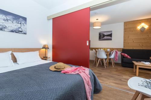 um quarto de hotel com uma cama e uma parede vermelha em Résidence Odalys L'Ouillon em Saint-Sorlin-dʼArves