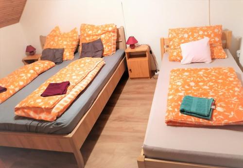 two beds in a room with orange pillows at Barackos Vendégház Bár in Bár