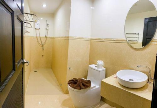 a bathroom with a toilet and a sink and a mirror at Cupid Hotel in Ban Thung Yao