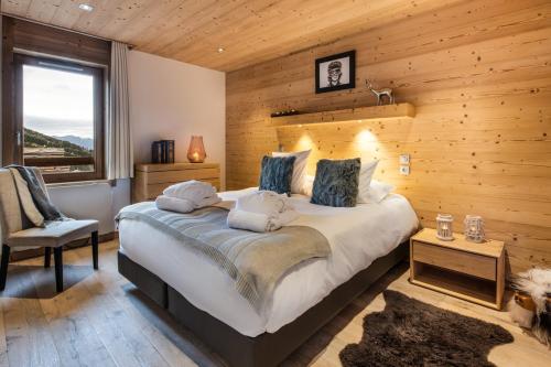 een slaapkamer met een groot bed en een houten muur bij Whistler Lodge by Alpine Residences in Courchevel