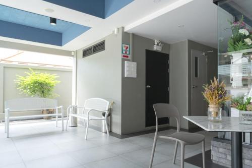 a dining room with white chairs and a table at The Home Hotel SHA in Bangkok