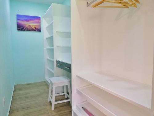 a walk in closet with white shelves and a stool at Casa De Leela Self Catering Guest House in La Digue