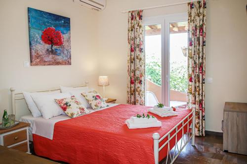 a bedroom with a bed with a red blanket and a window at Navigator Villas - Houses in Acharavi