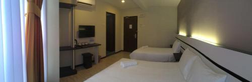 a hotel room with a bed and a television at Grand Kapar Hotel Kuala Selangor in Kuala Selangor
