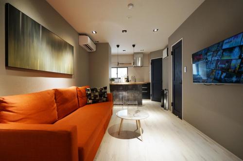 a living room with an orange couch and a table at Real Life Meguro River in Tokyo