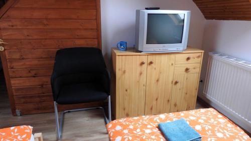 a room with a chair and a television on a dresser at Barackos Vendégház Bár in Bár