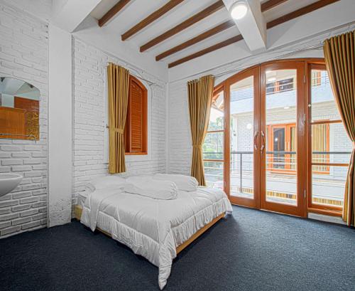 a bedroom with a bed and a sink and windows at DJourney Hotel Lembang by Escotel in Bandung