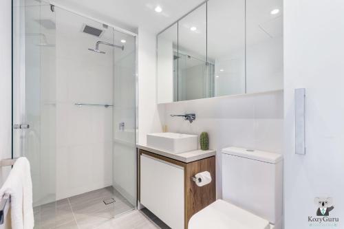 a white bathroom with a sink and a shower at KOZYGURU FORTITUDE VALLEY HOLIDAY STYLE 2 BED APT FREE PARKING QFV211-1601 in Brisbane