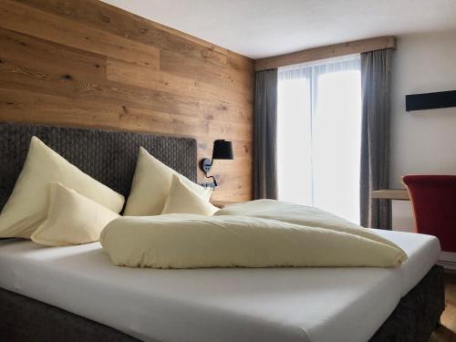 a bedroom with a white bed with a wooden wall at stefan Hotel in Sölden