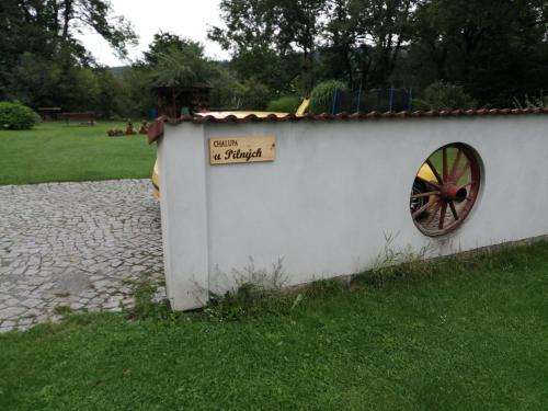 a white building with a wagon wheel in the grass at Chalupa u Pilných in Kaplice
