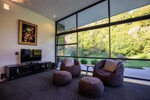 a living room with two chairs and a flat screen tv at The Jewel of Akatarawa in Upper Hutt