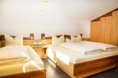 a bedroom with two beds with white sheets at Haus Tirol in Kappl