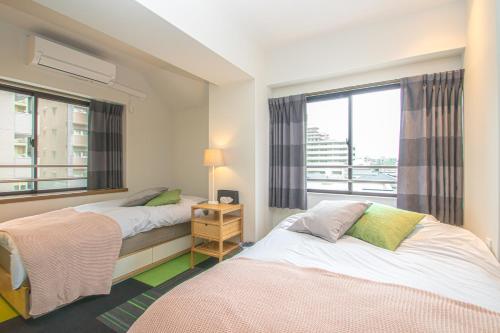 a bedroom with two beds and a window at AMP FLAT Nishijin 3 in Fukuoka