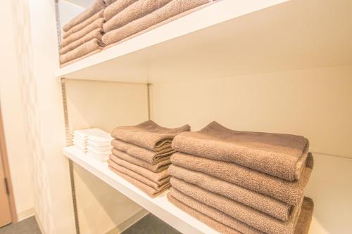 a pile of towels on a shelf in a bathroom at AMP FLAT Nishijin 3 in Fukuoka