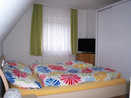 Schlafzimmer mit einem Bett mit bunter Bettwäsche und einem Fenster in der Unterkunft Das Steghaus in Gräfenberg
