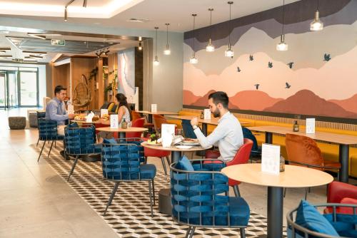 people sitting at tables in a restaurant with blue chairs at Novotel Gaziantep in Gaziantep