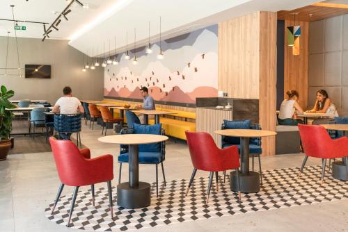 a restaurant with red and blue chairs and tables at Novotel Gaziantep in Gaziantep