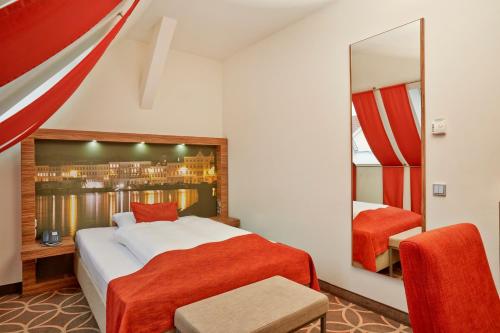a bedroom with a large bed and a mirror at H+ Hotel Lübeck in Lübeck