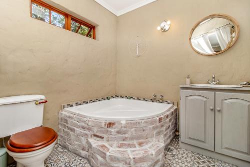 y baño con bañera de ladrillo, aseo y lavamanos. en Villa Roma - Luxury Accommodation, en Centurion