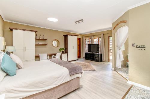 una camera con un grande letto e una televisione di Villa Roma - Luxury Accommodation a Centurion